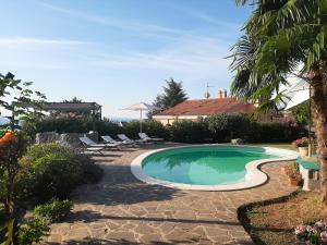 a swimming pool in a yard with chairs and the ocean at B&B Eva in Ičići