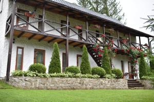 une maison dotée d'un mur en pierre et de fleurs. dans l'établissement Zorianyy Guest House, à Mykulychyn