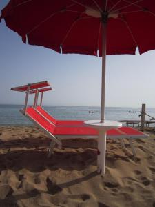 - une chaise de plage avec un parasol sur la plage dans l'établissement Hotel Masseria Fortificata Donnaloia, à Monopoli