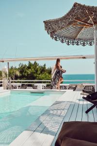 a woman is sitting next to a swimming pool at Playa del Mar - Adults Only in Monopoli