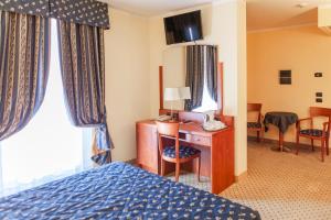ein Hotelzimmer mit Bett und Schreibtisch mit Telefon in der Unterkunft Hotel Olivo in Arco