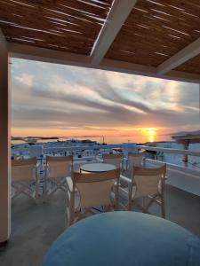 a balcony with tables and chairs and a sunset at Lefteris in Mikonos