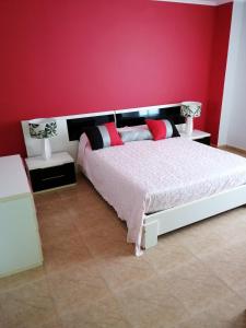 ein Schlafzimmer mit einem Bett und einer roten Wand in der Unterkunft Casa Iglesias en pantin in Valdoviño