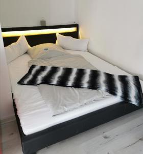 a bed with black and white sheets and pillows at Arthouse Apartment 2 in Bad Vilbel