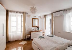 a white bedroom with a bed and a vanity and windows at Apartment Teatar in Korčula