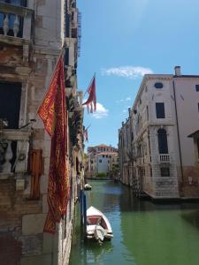un pequeño barco en un canal en una ciudad en Fiabe Venice Rooms en Venecia