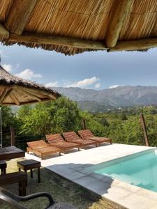 a pool with chairs and a view of the mountains at Los Remolinos in Merlo