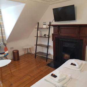 a living room with a fireplace with a tv above it at Ness City Cottage in Inverness