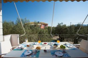 Santa Maria Luxury Apartments في ليفكادا تاون: طاولة على شرفة مع طعام عليها
