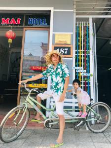 una mujer parada junto a una bicicleta con un niño en Hoa Mai Hotel, en Dong Hoi