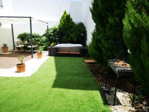 un jardín con césped verde, una cama y una tienda de campaña en Aracena Suites, en Aracena