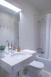 a white bathroom with a sink and a toilet at República Bed & Breakfast in Lisbon