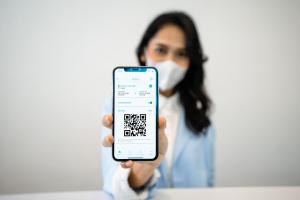 a woman in a mask holding a phone with a text message on it at Bobopod Pancoran, Jakarta in Jakarta