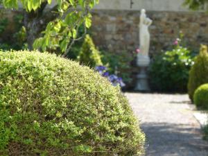 a hedge in a garden with a statue in the background at La Roseraie in Saint-Étienne-au-Mont