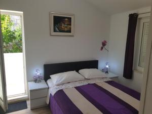 1 dormitorio con 1 cama con manta morada y blanca en Guesthouse Perica, en Dubrovnik