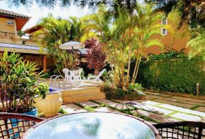 a patio with a table and chairs in a garden at Pousada Genesis in Arraial do Cabo