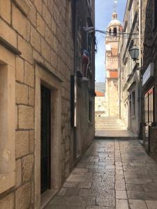 an alley with a building and a tower in the distance at Apartment Teatar in Korčula