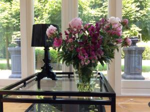 un jarrón de flores rosas sentado en una mesa de cristal en B&B de Tol, en Hulst