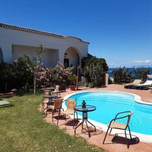 una piscina con tavoli e sedie accanto a una casa di B&B Villa Antica a Ischia