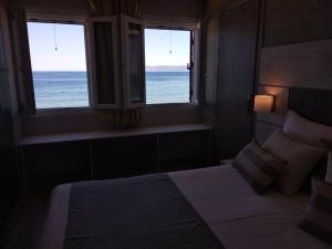 a bedroom with a bed and two windows with the ocean at Apartment Toula in Petra