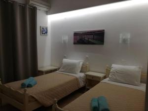 イオス島 チョーラにあるGalini Pensionのベッド2台が備わる客室で、壁には絵画が飾られています。