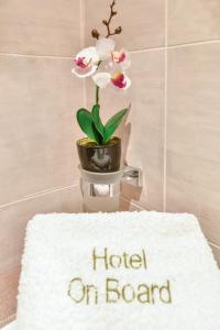 a sign for a hotel on board with a potted plant at On Board Luxury Studios in Sarti