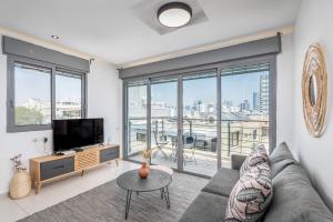 a living room with a couch and a tv at Superb 1,5 BDR W balcony close to the beach in Tel Aviv