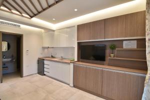 a kitchen with wooden cabinets and a flat screen tv at On Board Luxury Studios in Sarti