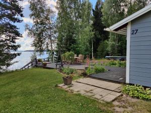 un patio trasero con una terraza de madera junto al agua en Villa Kesäranta, en Jämsä
