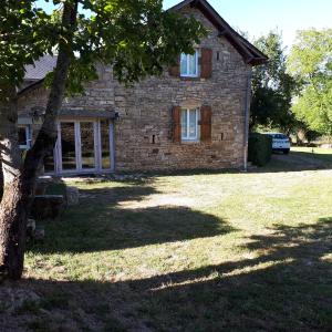 a stone house with a tree in front of it at Gîte La Grange in Saint-Laurent-dʼOlt