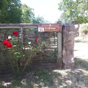 uma cerca com rosas com um sinal em Gîte La Grange em Saint-Laurent-dʼOlt