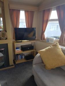 a living room with a couch and a flat screen tv at Haven Devon Cliffs Caravan in Budleigh Salterton
