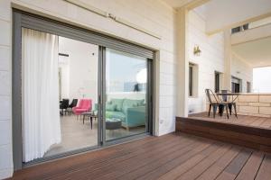 a sliding glass door on a deck with a living room at Stylish Garden Apartment Close to Akhziv Beach by Sea N' Rent in Nahariyya