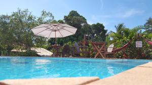 - une piscine avec des chaises et un parasol dans l'établissement Pousada Tubarão, à Arraial d'Ajuda