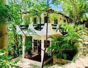 a white house in the middle of trees at Casa Il Tucano in Puerto Ángel