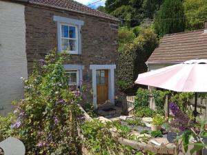 a house with an umbrella and flowers in front of it at Sky Cottage in Fowey