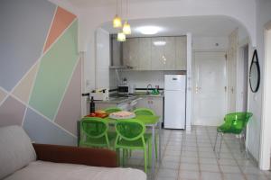 a kitchen with a table and green chairs in a room at Balcon del Mar en la Costa in Costa Del Silencio