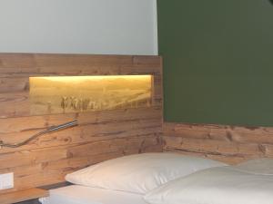 a bed with a wooden headboard with a picture on the wall at Hotel & Gasthof Hubertushöhe - Ihr Hotel für Urlaub mit Hund in Schmallenberg
