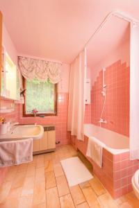 een roze badkamer met een bad en een wastafel bij Ferienhäuschen Sans Pareille bei Bayreuth in Hartmannsreuth