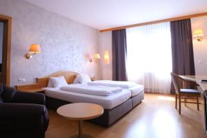 ein Hotelzimmer mit 2 Betten und einem Sofa in der Unterkunft Stadthotel Pinkafeld in Pinkafeld