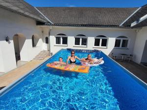 a woman and two children playing in a swimming pool at Artemis Farmapartment in Bad Blumau