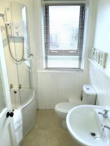 a white bathroom with a toilet and a sink at Benside Cottage in Stornoway