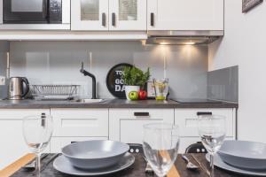 Una cocina con gabinetes blancos y una mesa con copas de vino. en Sunflower Apartment Old Town, en Cracovia