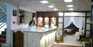 a woman standing at a counter in a kitchen at Katerina Hotel in Kozani