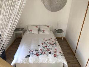 - une chambre dotée d'un lit avec un couvre-lit floral dans l'établissement La Maisonnette auvergnate, à Vertaizon