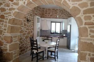 uma cozinha com uma mesa e cadeiras numa parede de pedra em Traditional stone house em Sitia