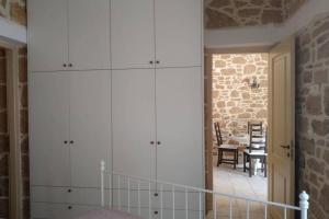 Traditional stone house في سيتيا: غرفة بها دواليب بيضاء وجدار من الطوب
