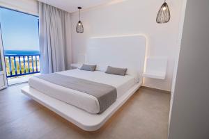 ミコノス・シティにあるAeolos Resortの白いベッドルーム(ベッド1台、大きな窓付)