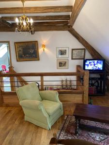 un salon avec une chaise verte et une télévision dans l'établissement Maison d'hôtes Moulin du Bas Pesé, à Mont-près-Chambord