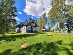 a small house on a grassy field next to a lake at Topin Tuvat in Oravisalo